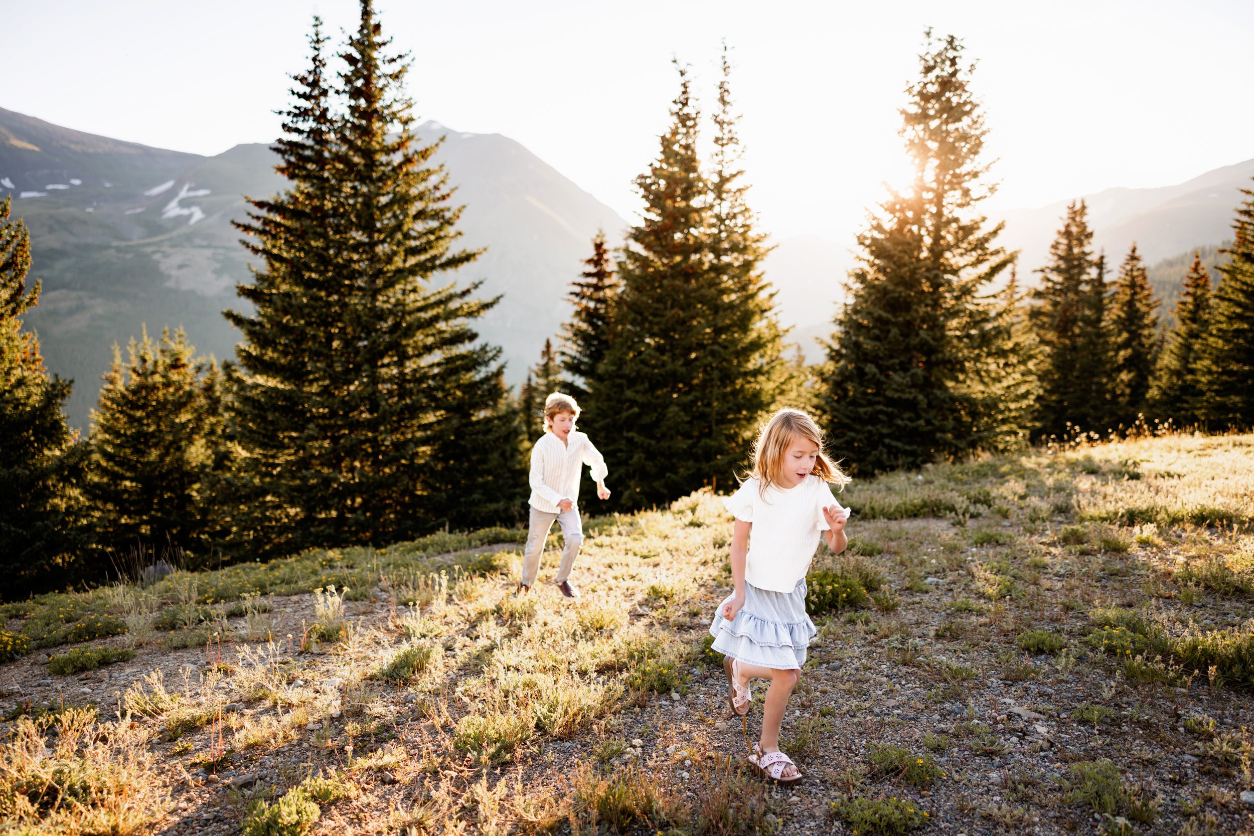 Siblings running through a glowing alpine meadow at Hoosier Pass