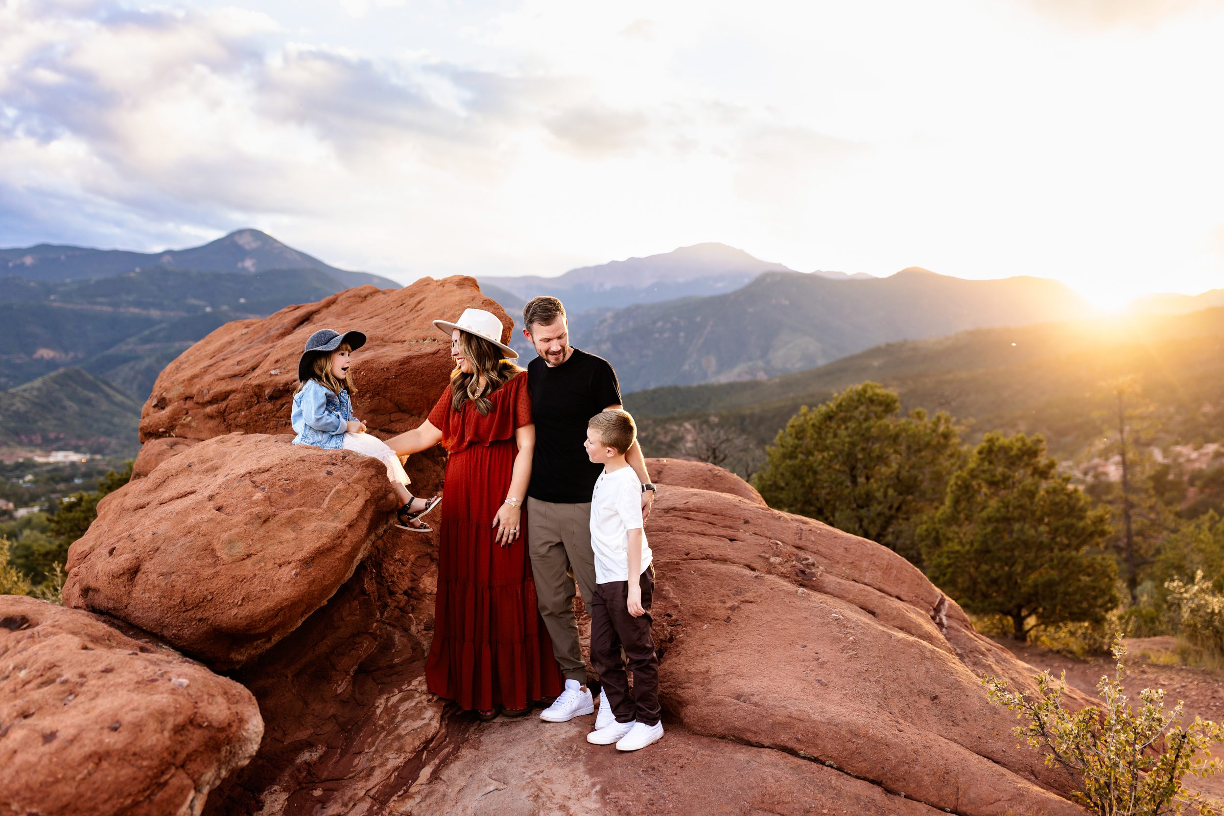 Garden of the Gods family photos of a family standing together on red rock formations with mountain views at sunset