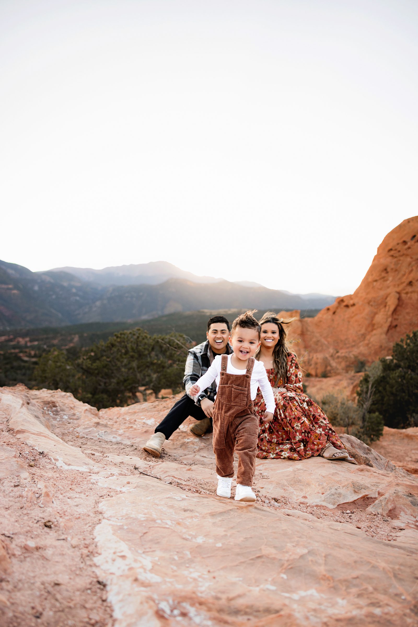 Smiling toddler running away from parents during a mini session at Garden of the Gods