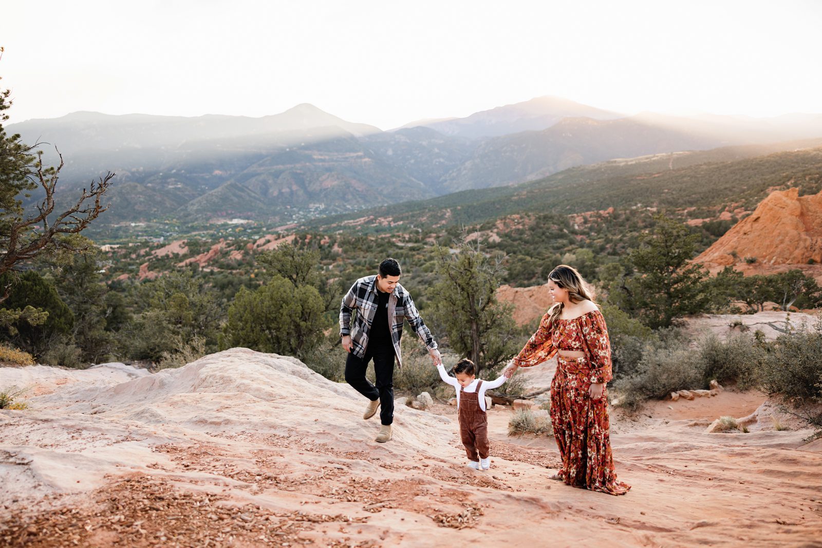 Garden of the Gods Mini Session family walking together across red rock terrain with mountain views
