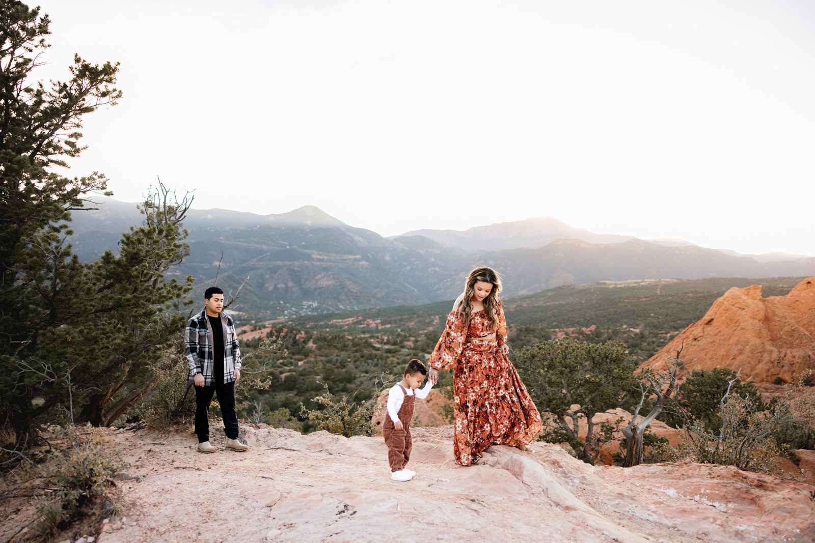 Garden of the Gods Mini Session mom holding toddler’s hands with red rock views in the background