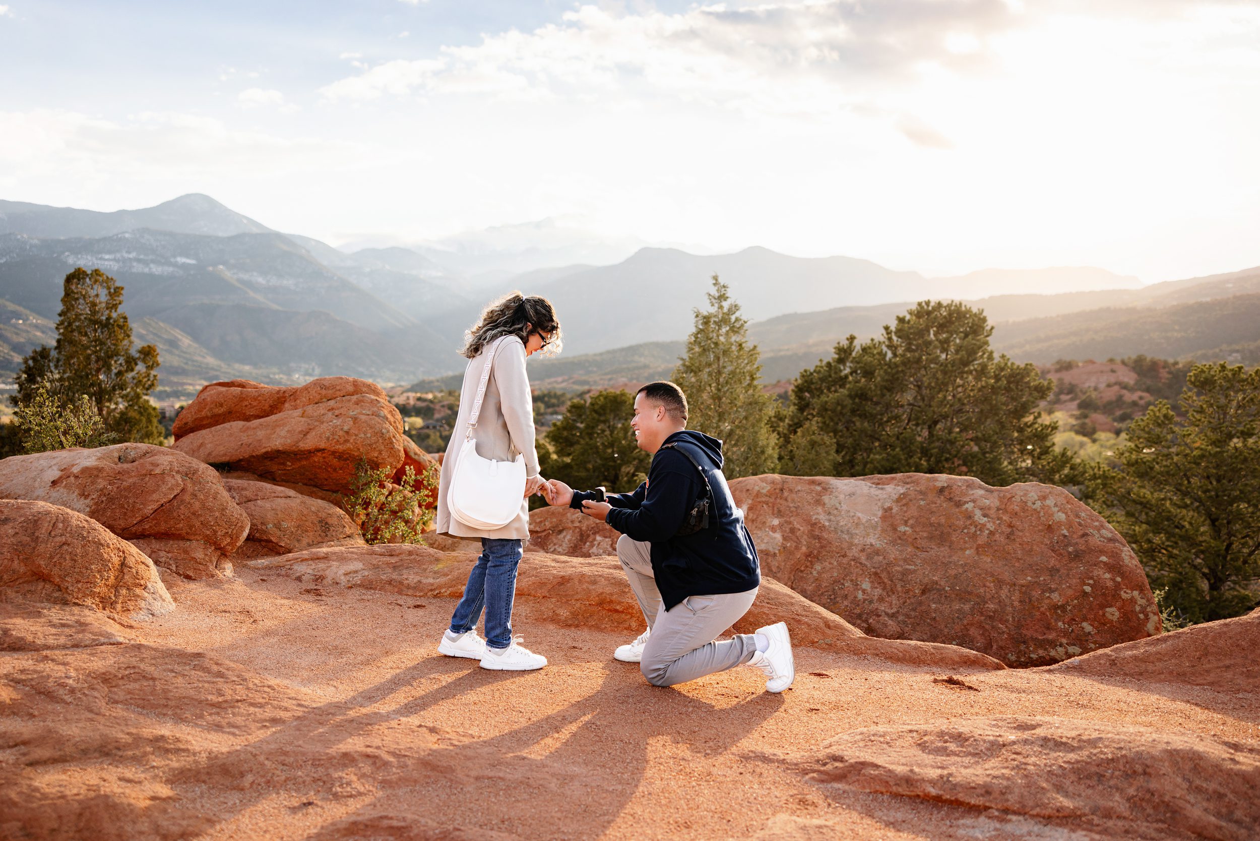 Man proposing on red rocks at sunset with mountain views in Garden of the Gods proposal photos