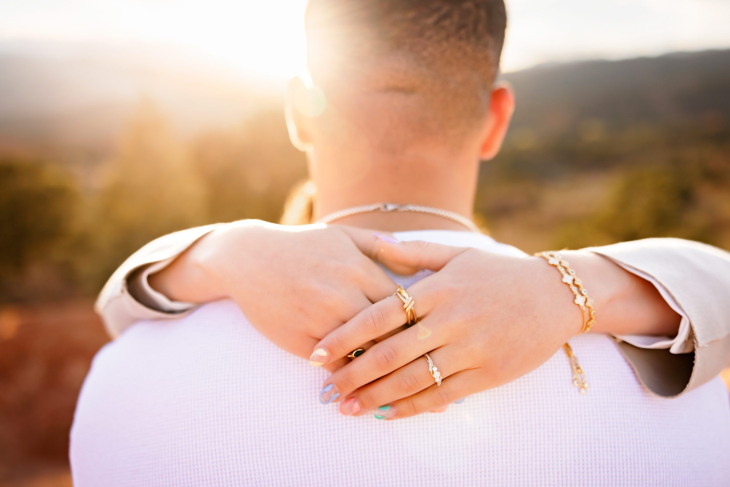 Close up of engagement ring on woman’s hand during golden hour proposal moment