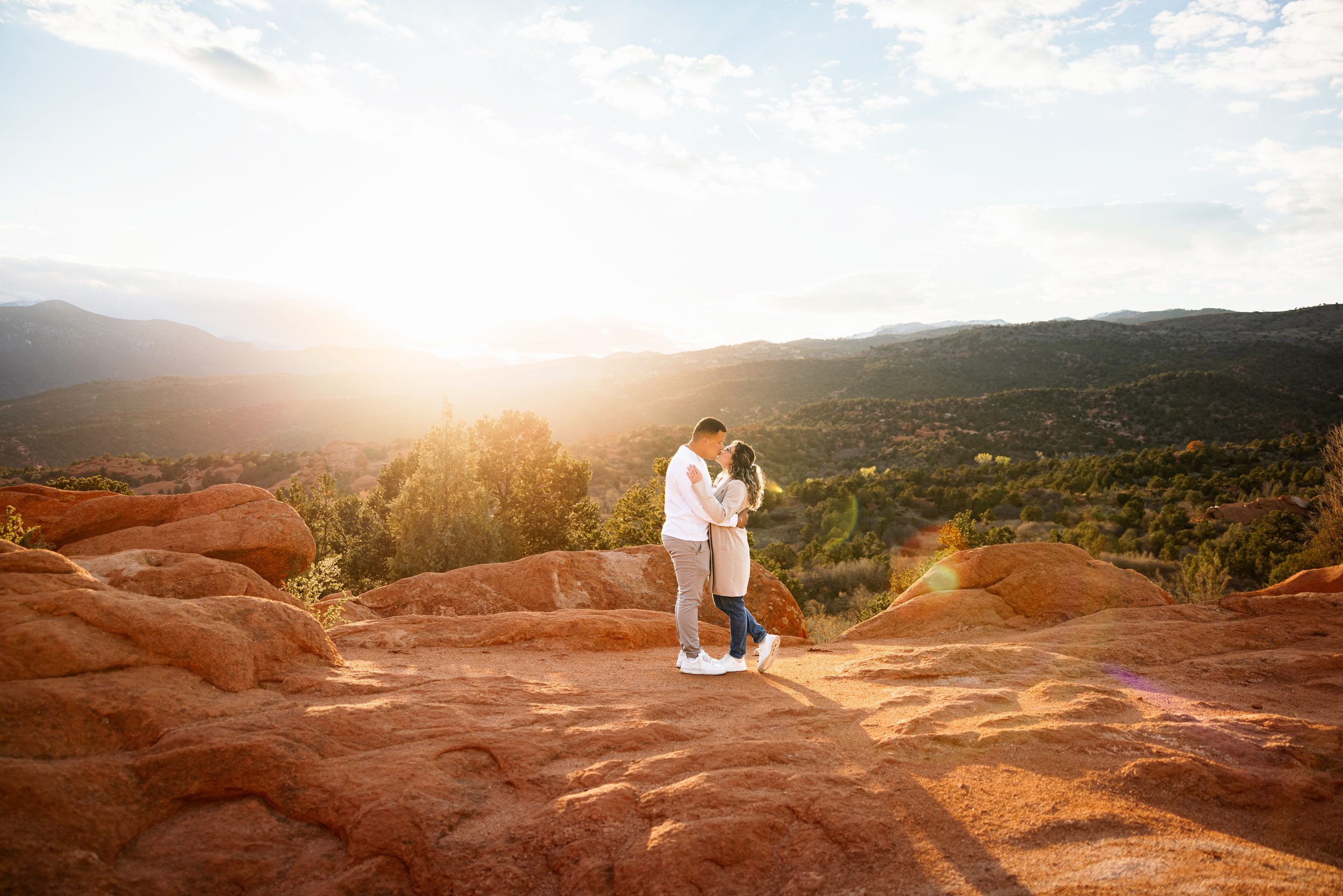 Couple embracing at sunset with glowing light and mountain backdrop in Garden of the Gods proposal photos