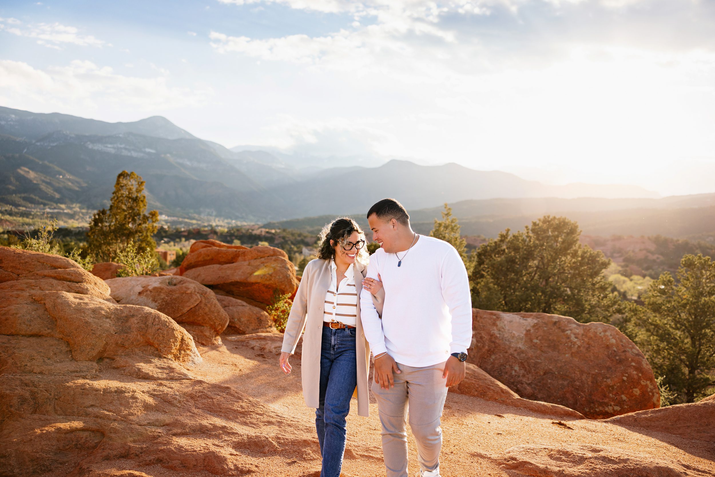 Couple walking together on red rocks during golden hour in Colorado Springs