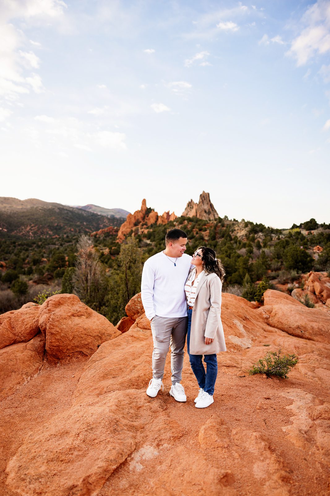 Couple standing together on red rocks with iconic Garden of the Gods formations in the background