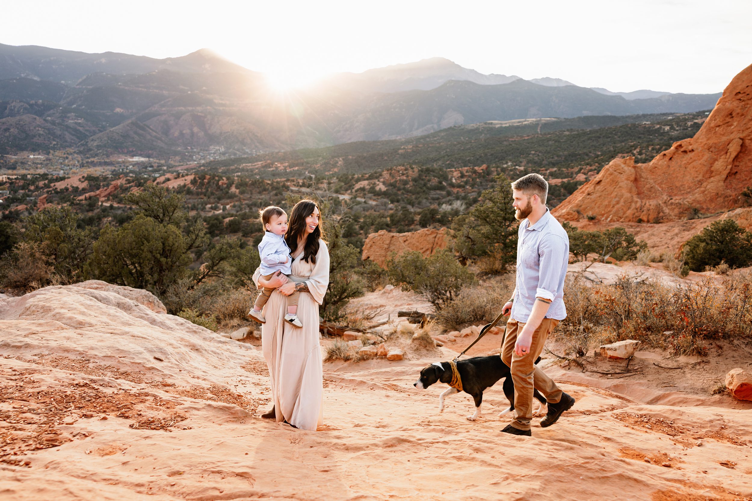 Family walking with their dog on a red rock trail at sunset with mountain views in Colorado Springs