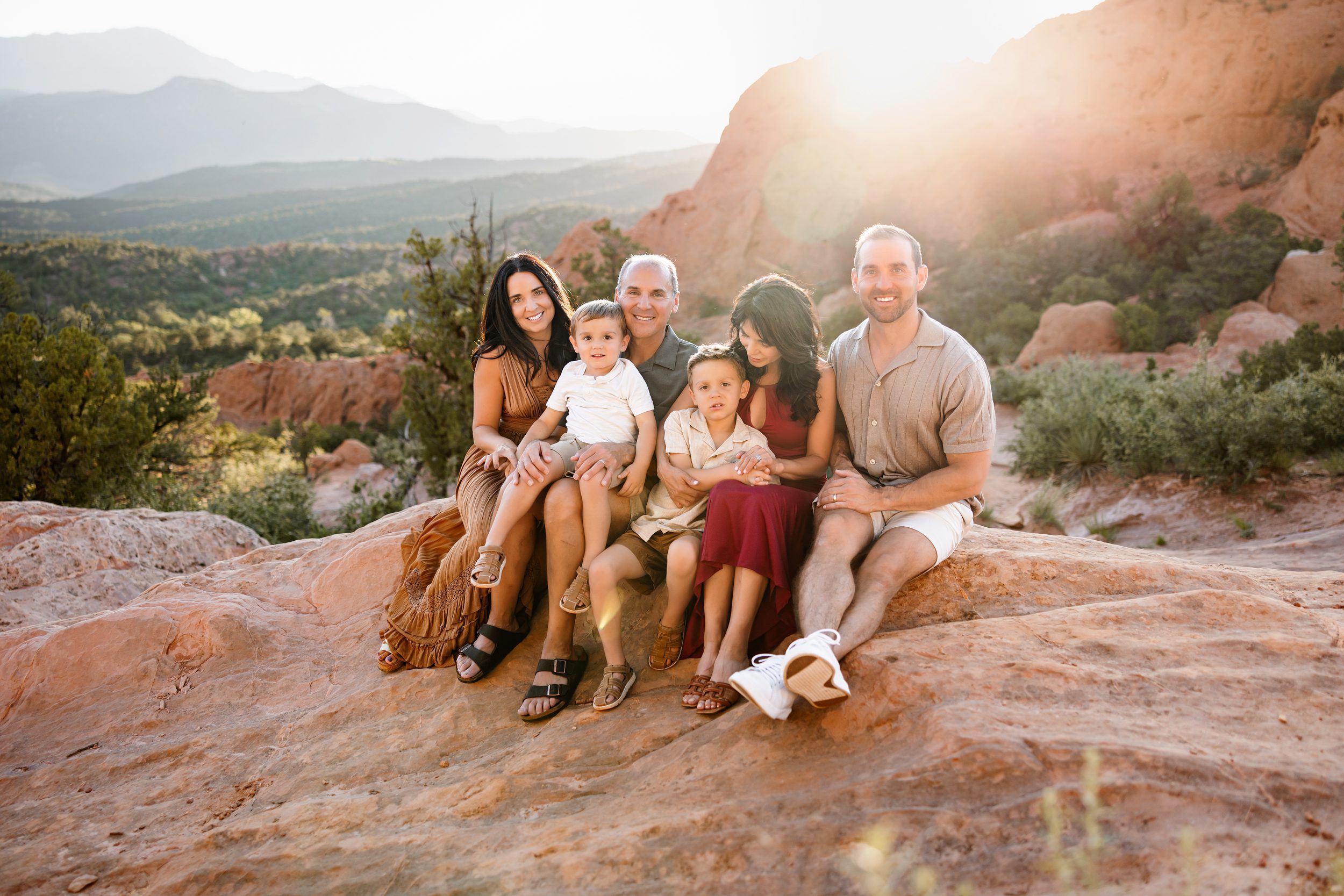Family sitting together on red rocks with warm sunset light and mountain views in the background