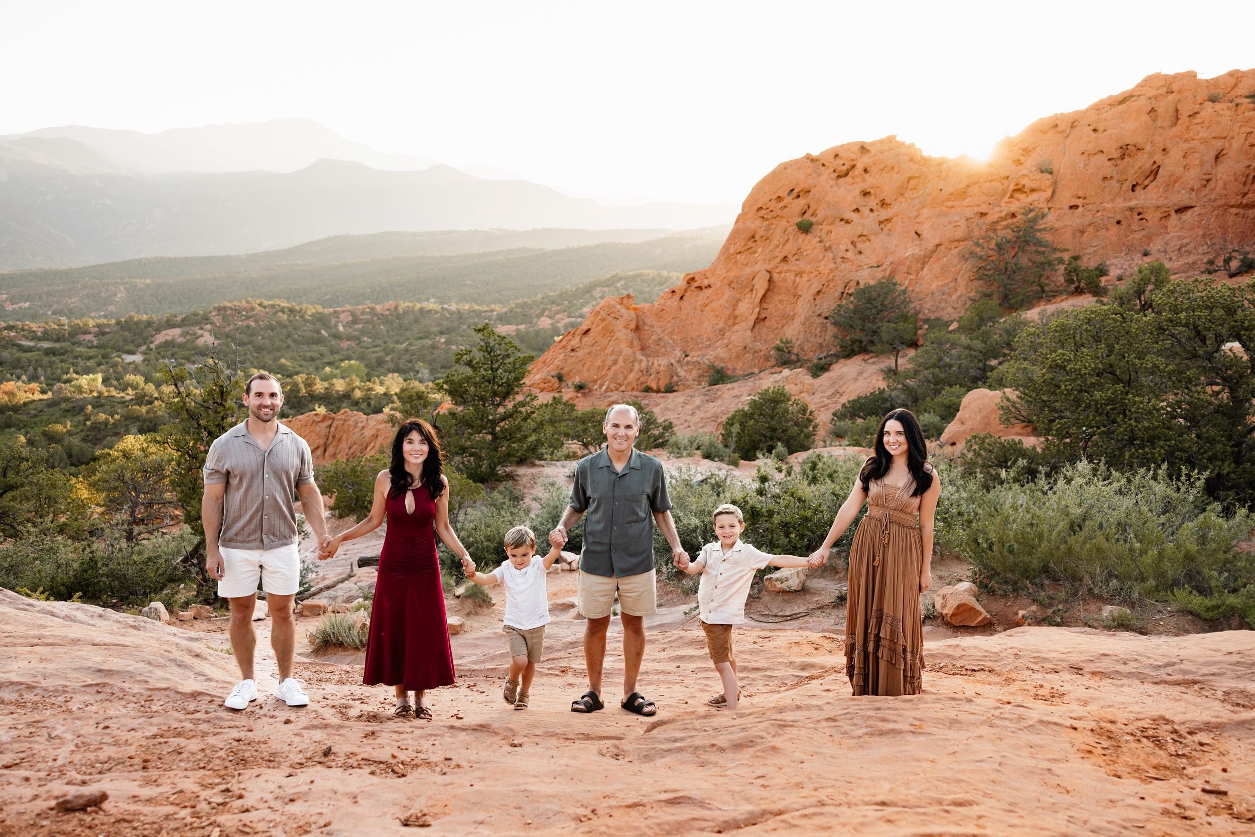 Full family holding hands and walking together on a red rock trail in Colorado Springs