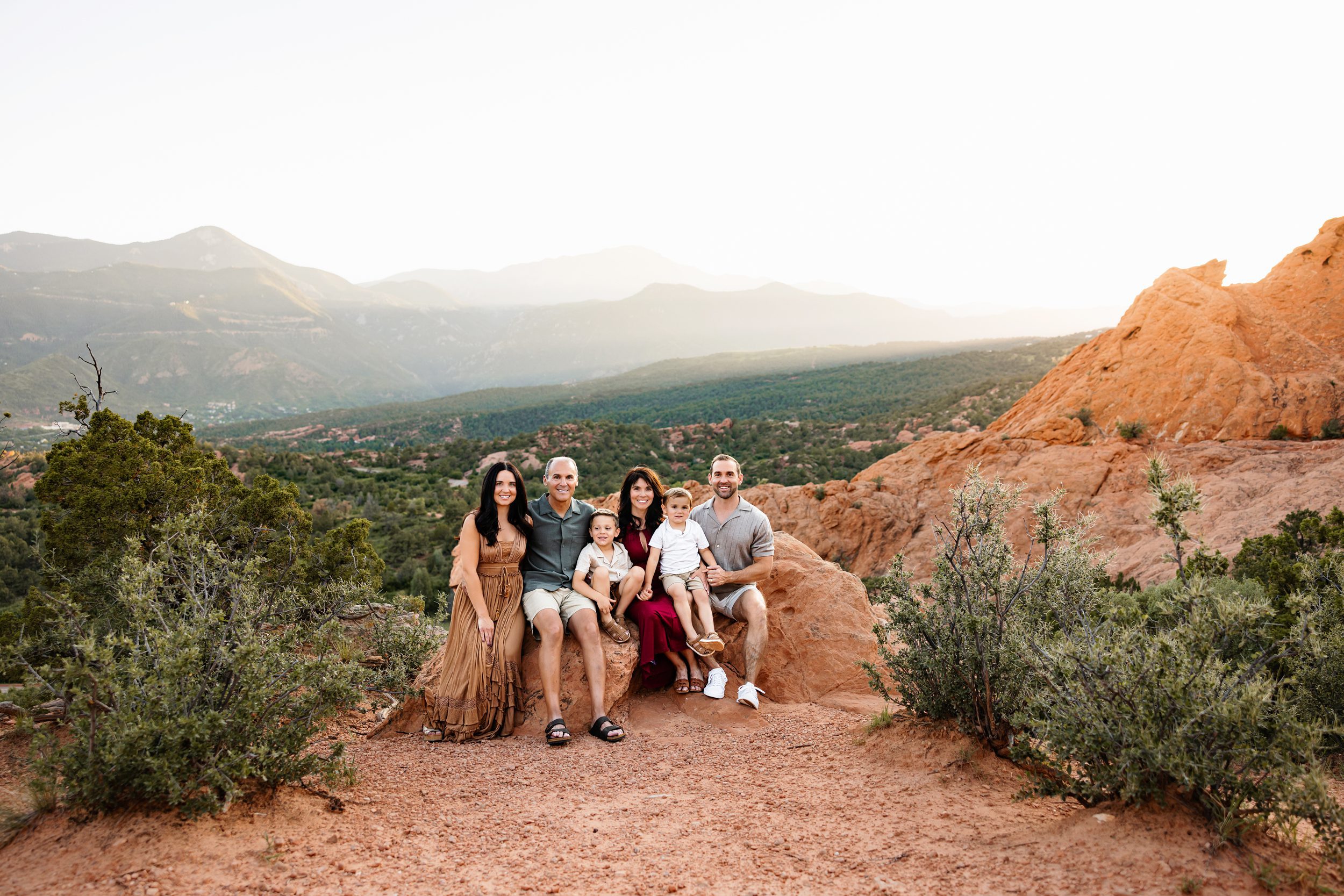 Parents and grandparents sitting with kids on rocks, including grandparents in your family photos at golden hour