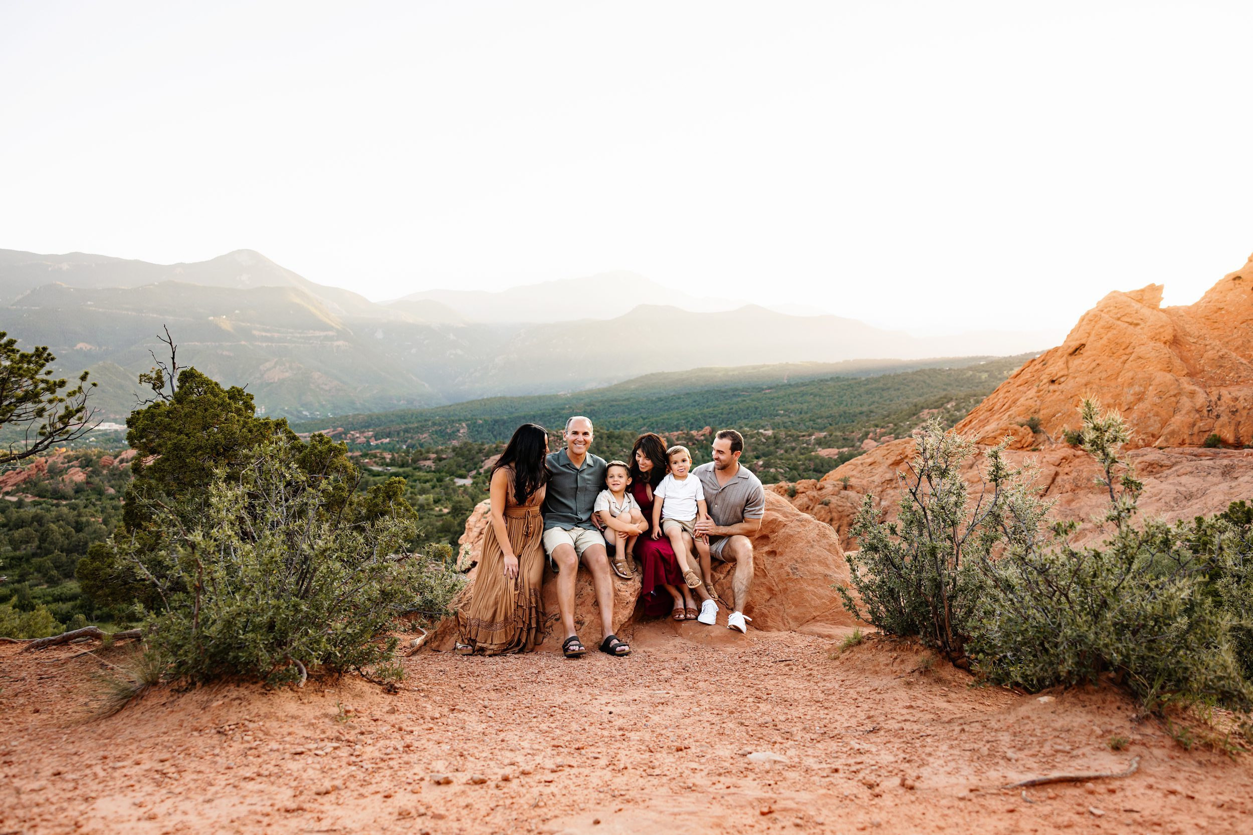 Extended family smiling together with mountain views and red rock backdrop in Colorado Springs