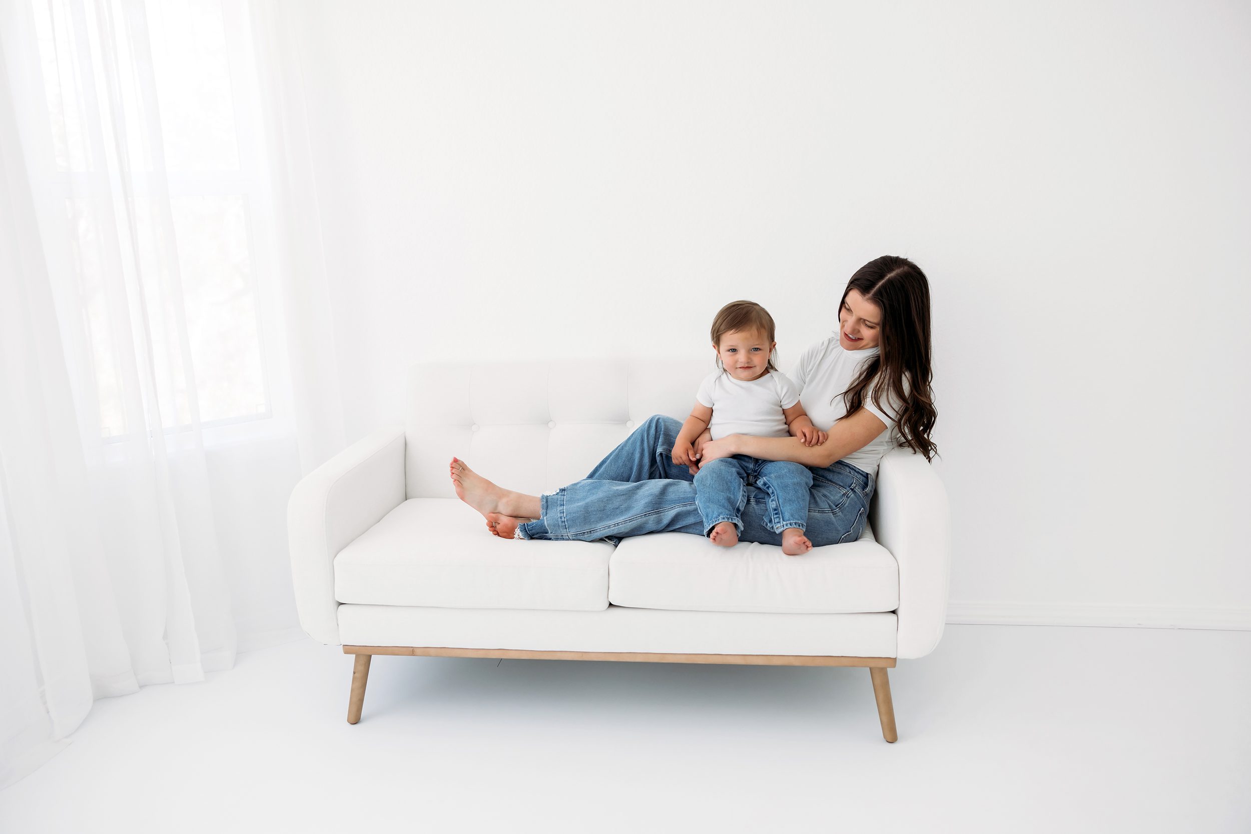 Studio Motherhood Photos in Colorado Springs showing a relaxed moment of mom and toddler sitting together on a couch