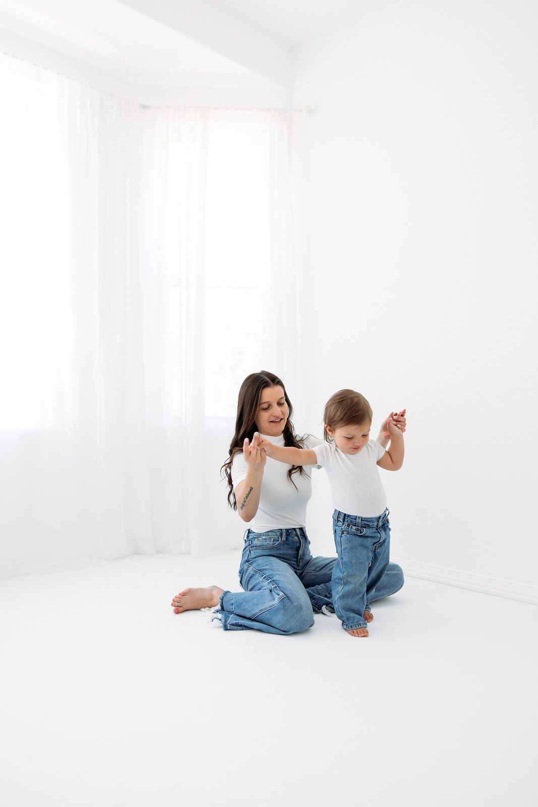 Studio Motherhood Photos in Colorado Springs featuring a mom helping her toddler take first steps