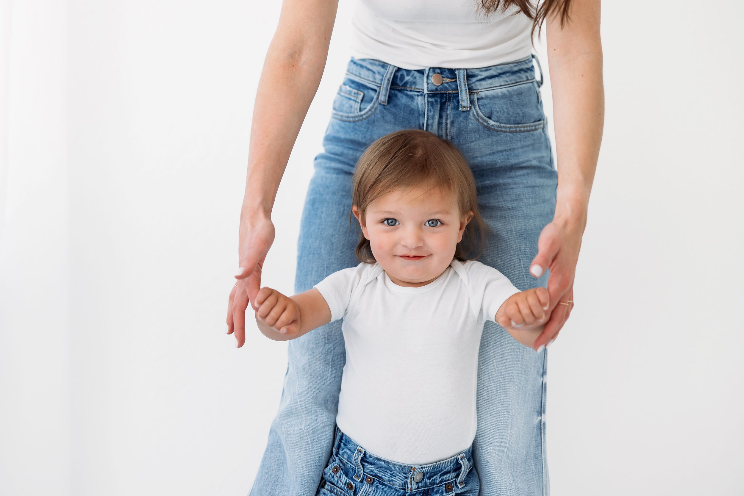 Studio Motherhood Photos in Colorado Springs of a mom guiding her toddler to walk