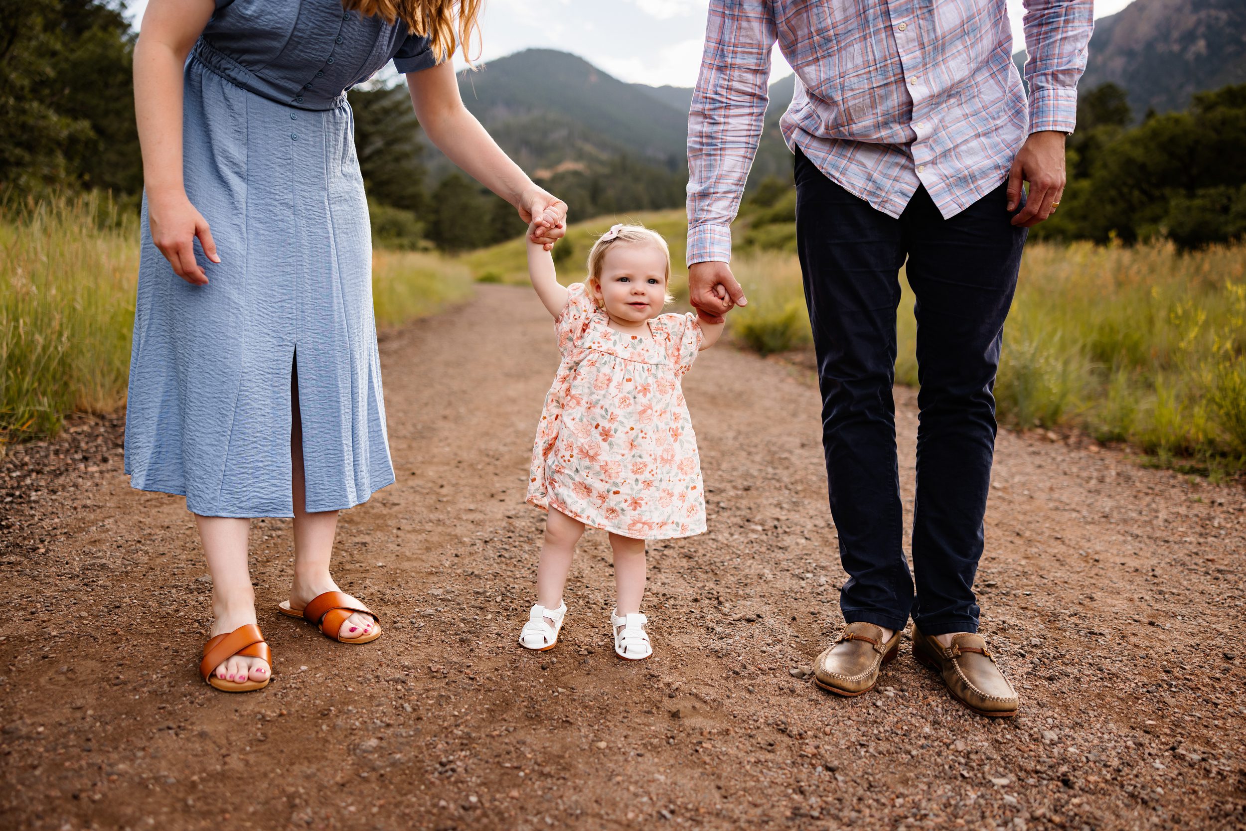 Summer Photo Session in Colorado Springs with parents walking along a dirt trail holding their baby girl