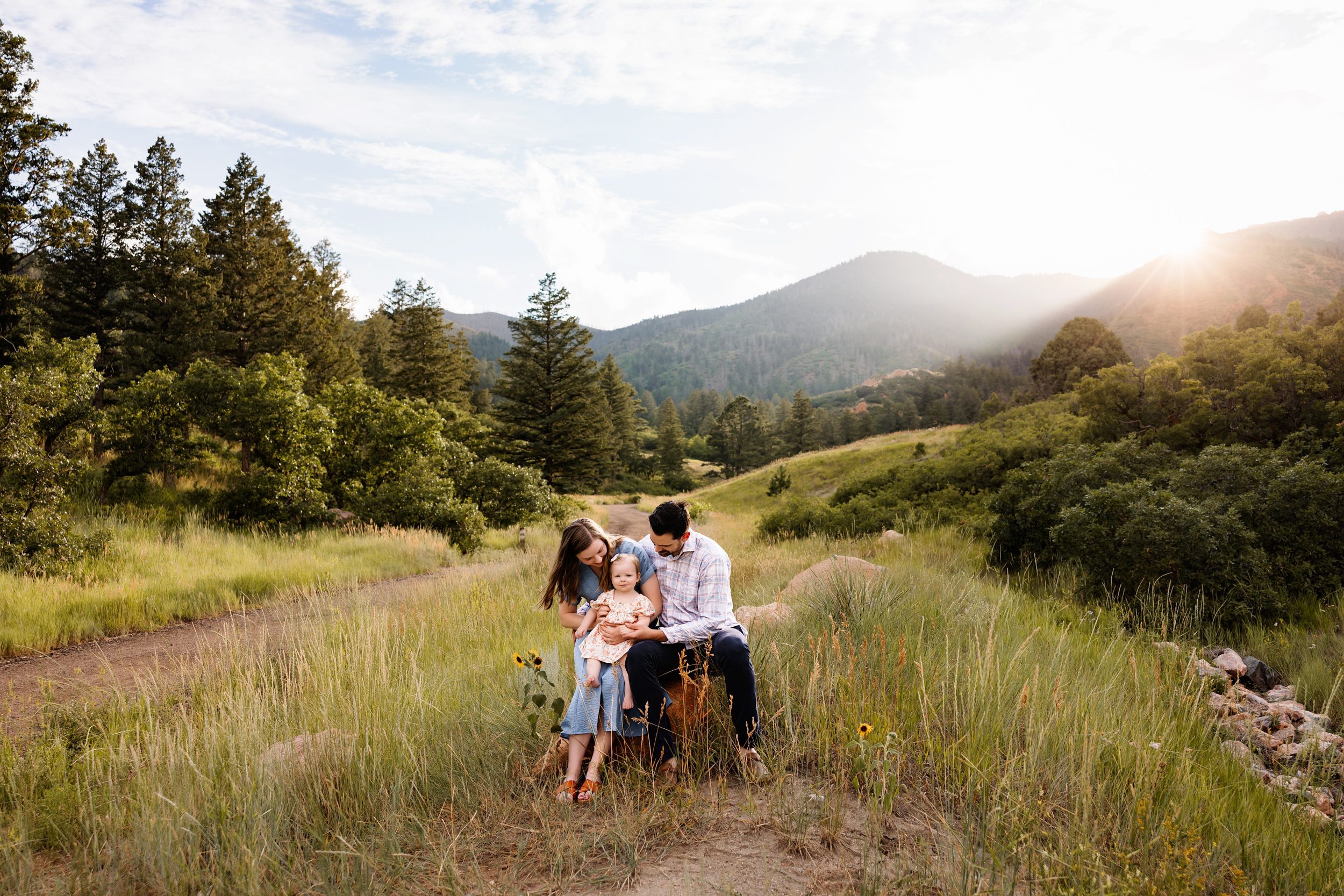 Summer Photo Session in Colorado Springs with a young family sitting together on a rock at sunset with soft mountain light