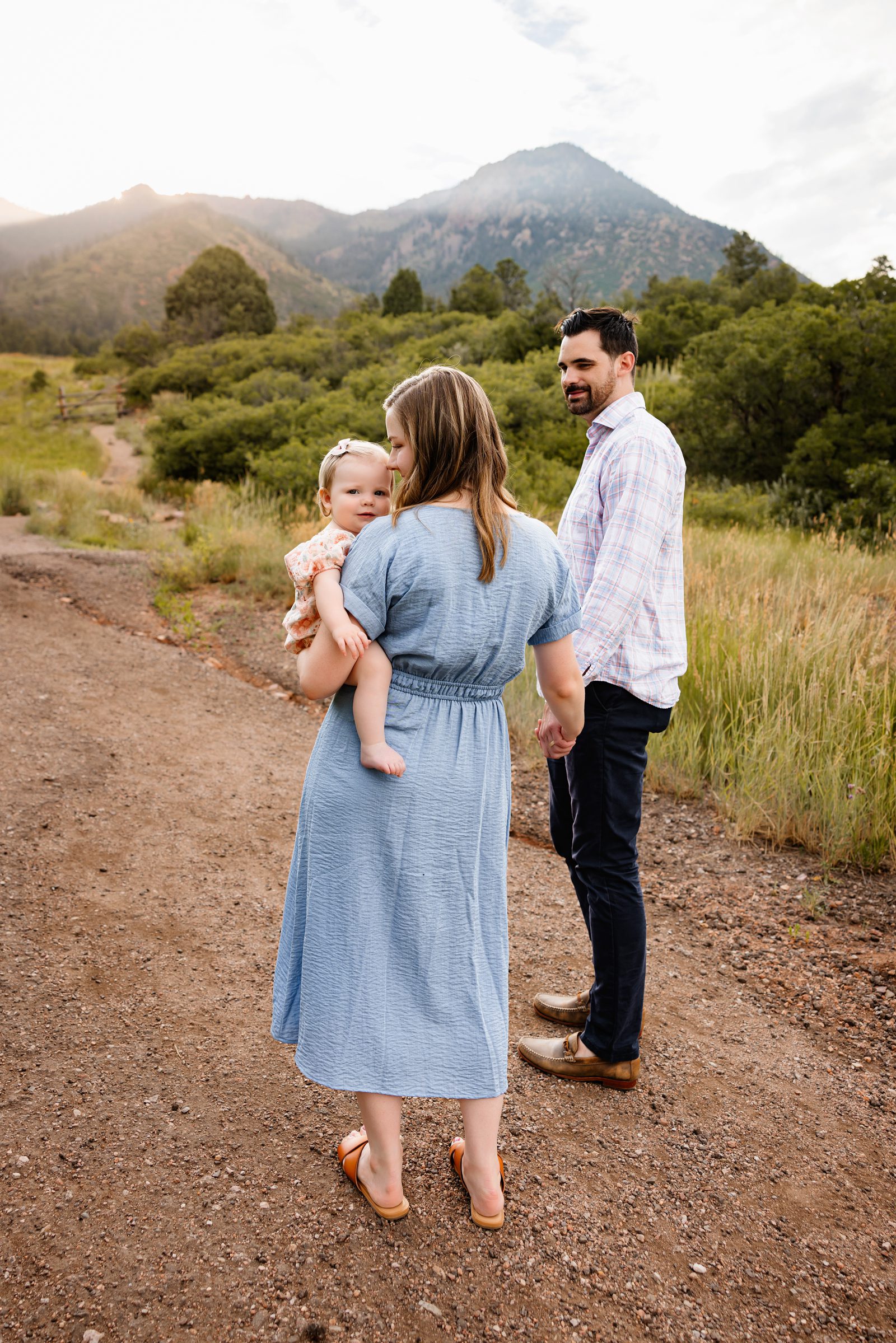 Summer Photo Session in Colorado Springs with parents walking along a dirt trail holding their baby girl