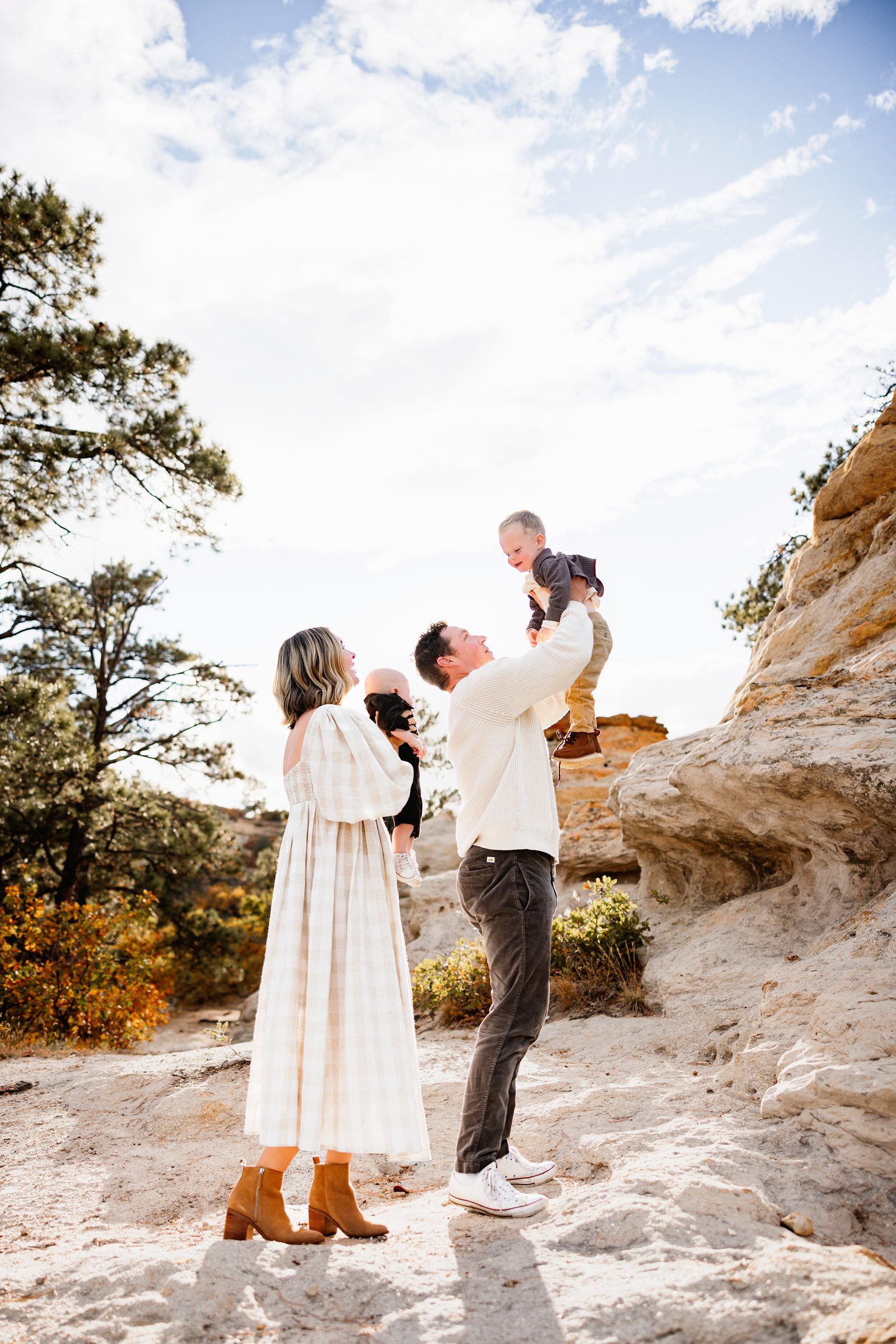 When to schedule your fall photos in Colorado shown through a joyful moment of dad lifting his child into the air with warm sunset light