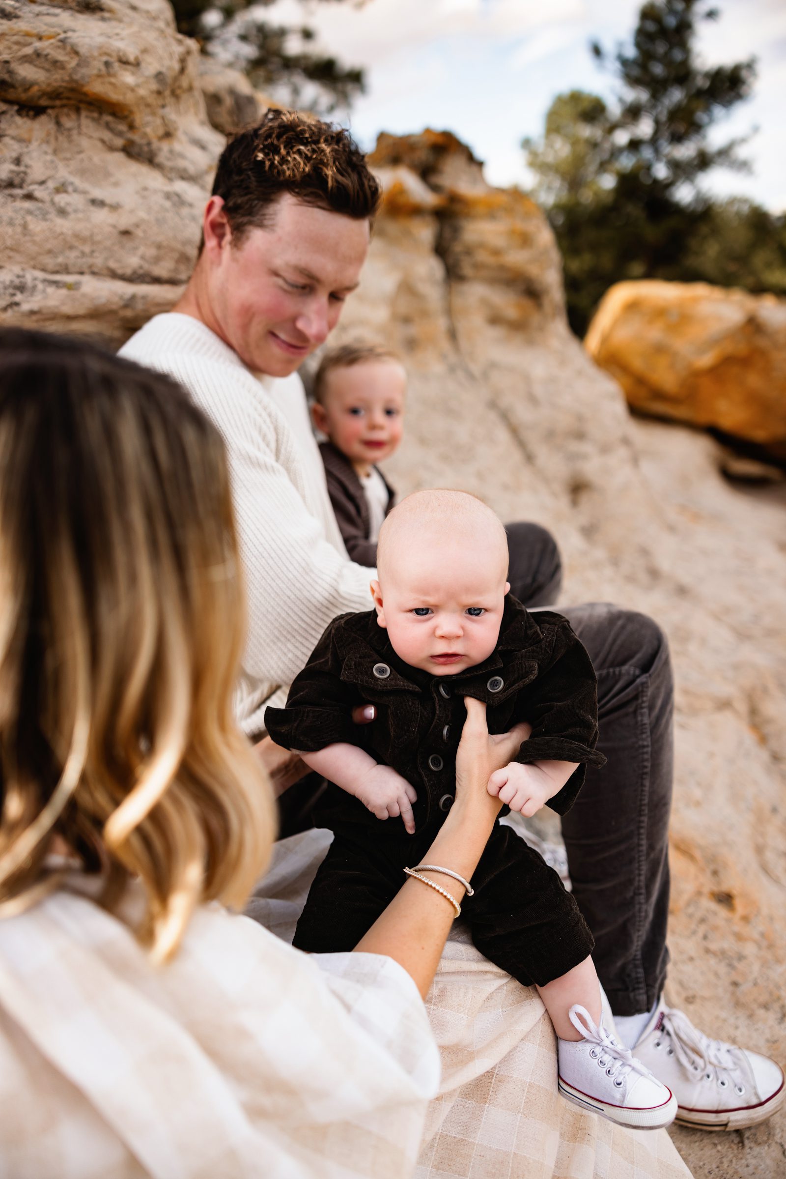 Close up of baby held by parents with soft background blur and warm earthy tones during a Colorado fall family photo session