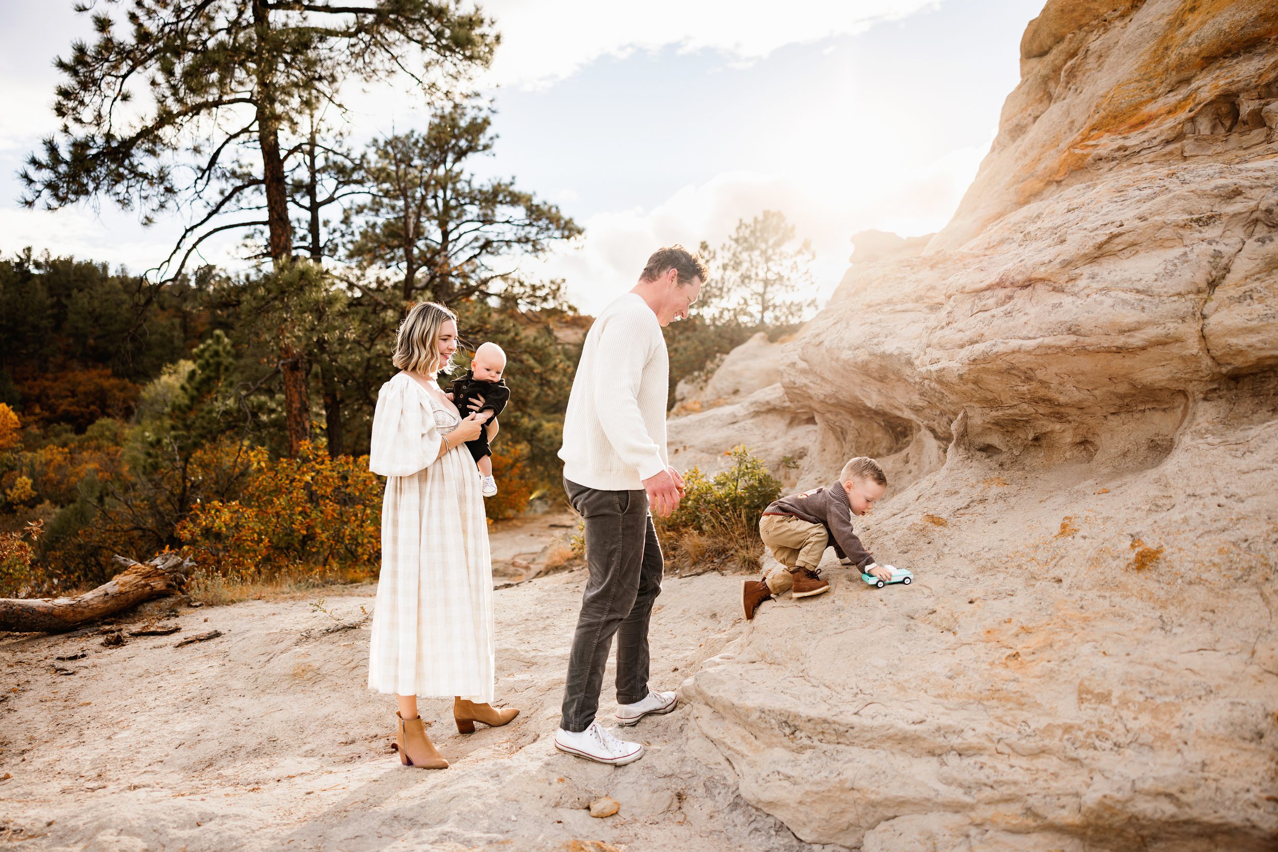 Family exploring sandstone formations at sunset with warm autumn colors and playful movement during a Colorado family photo session