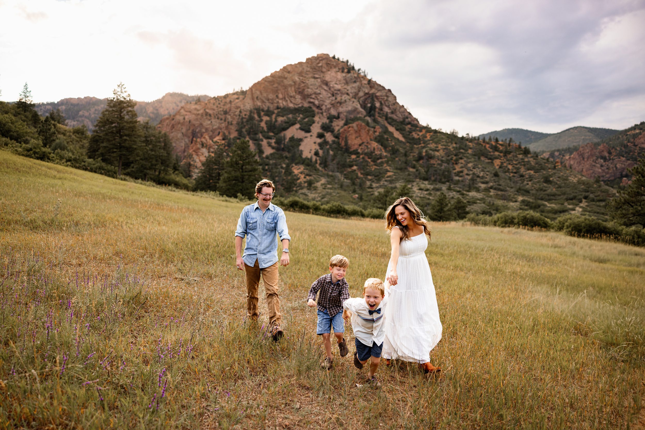 Playful family moment with kids running ahead while parents walk behind in a scenic Colorado meadow