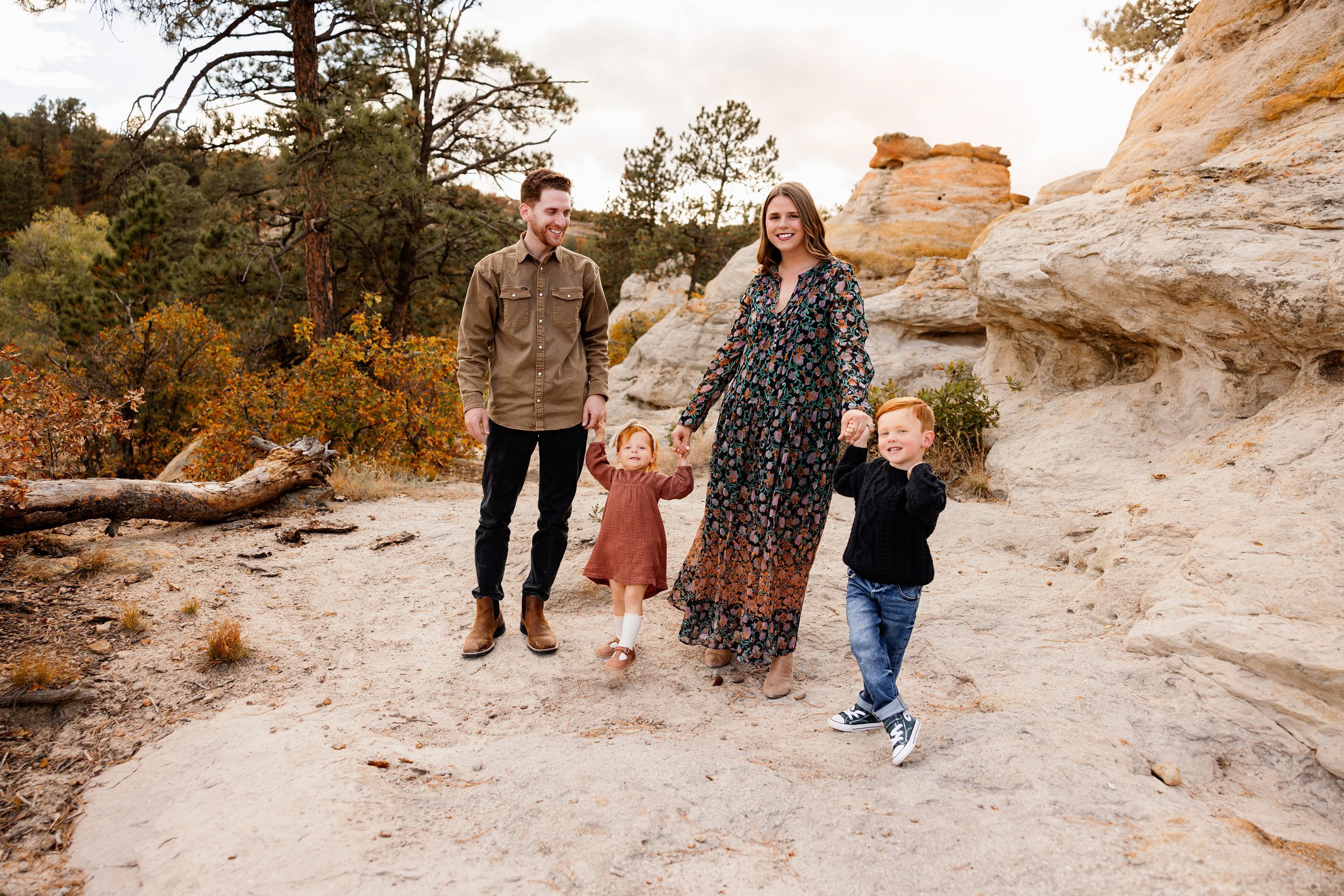 Photo session with toddler in Colorado Springs capturing a family laughing together on a sandy trail with warm fall tones