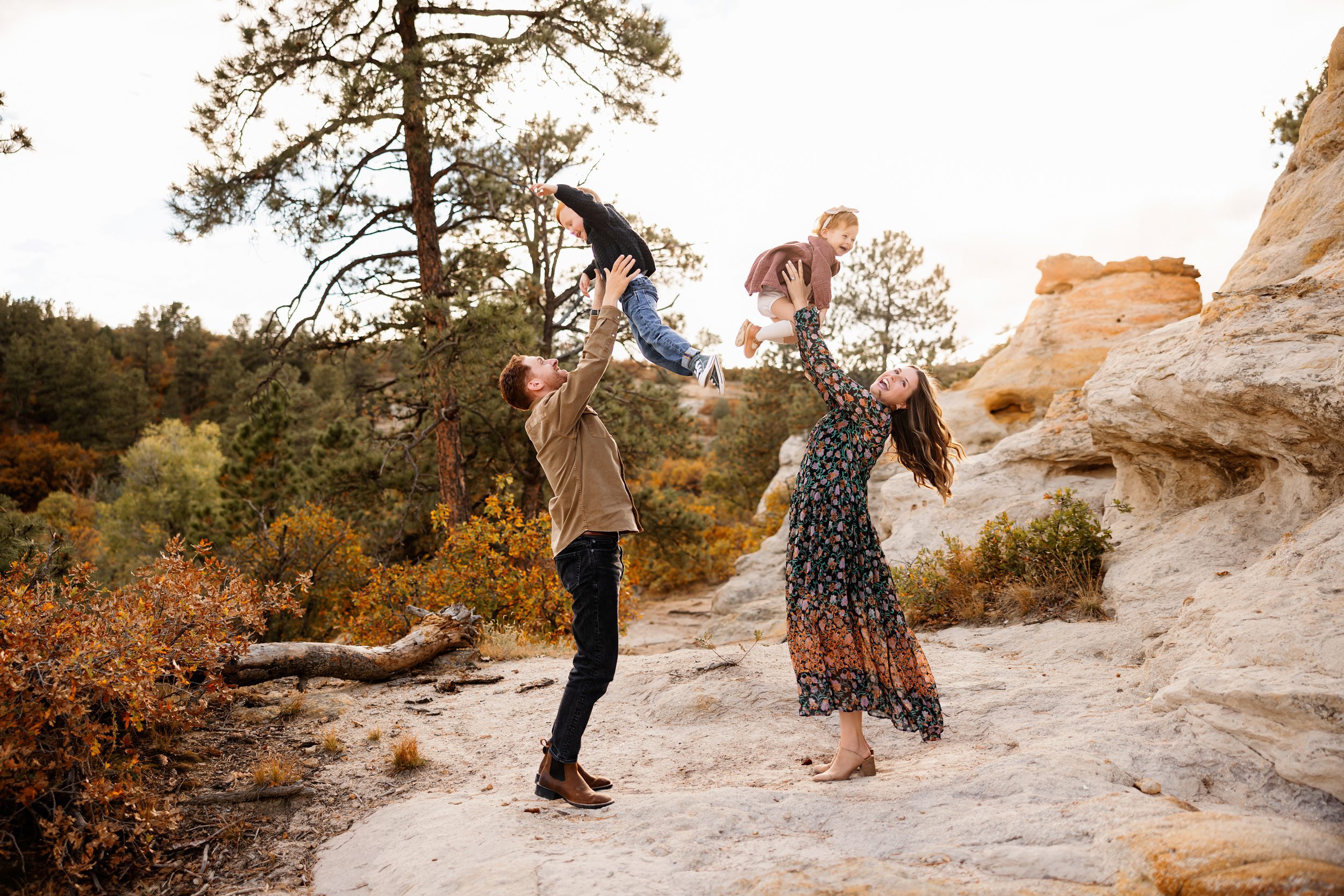 Photo session with toddler in Colorado Springs showing both parents tossing their kids up in a joyful candid moment