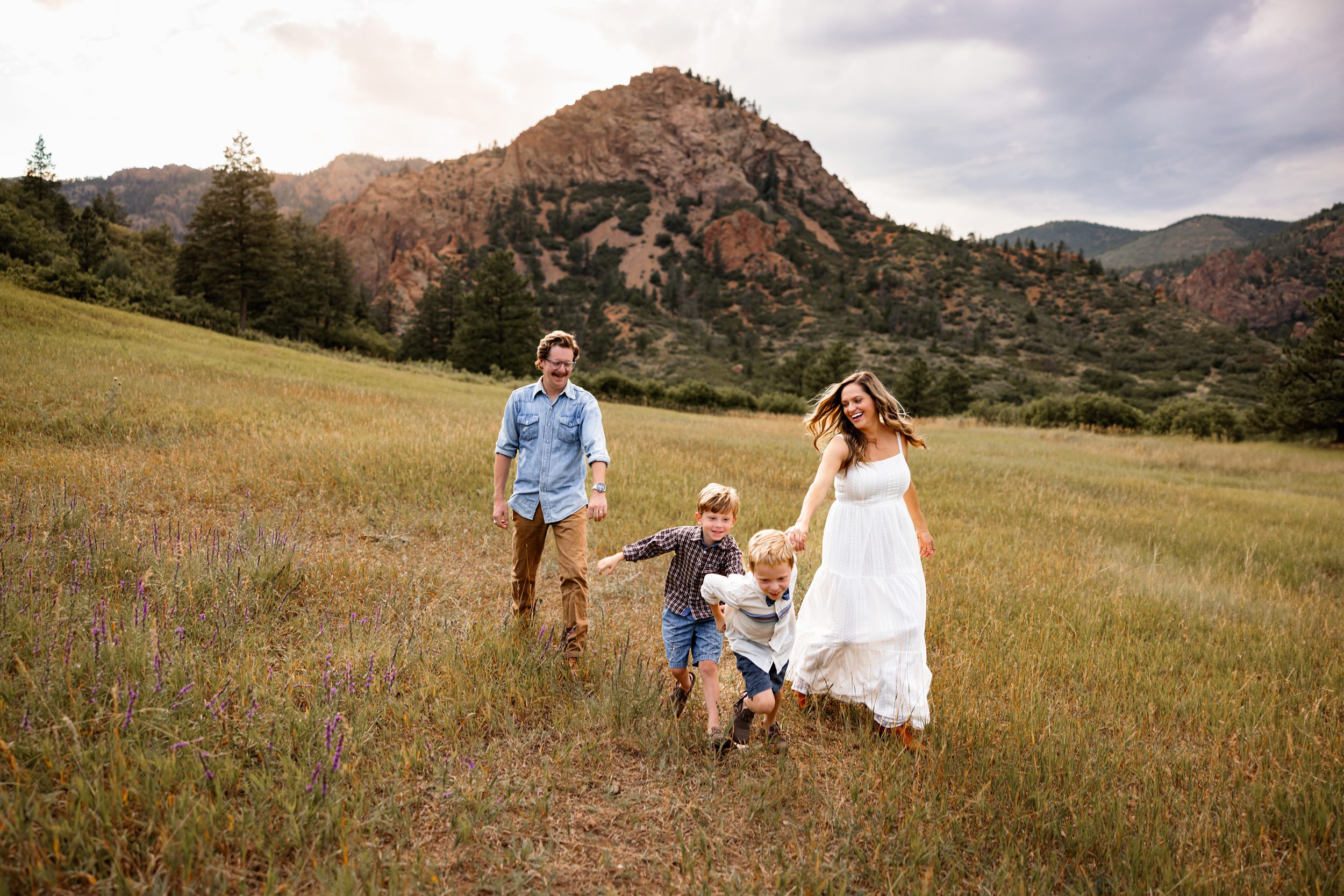 Summer photo locations in Colorado Springs featuring a family running through a mountain meadow at sunset