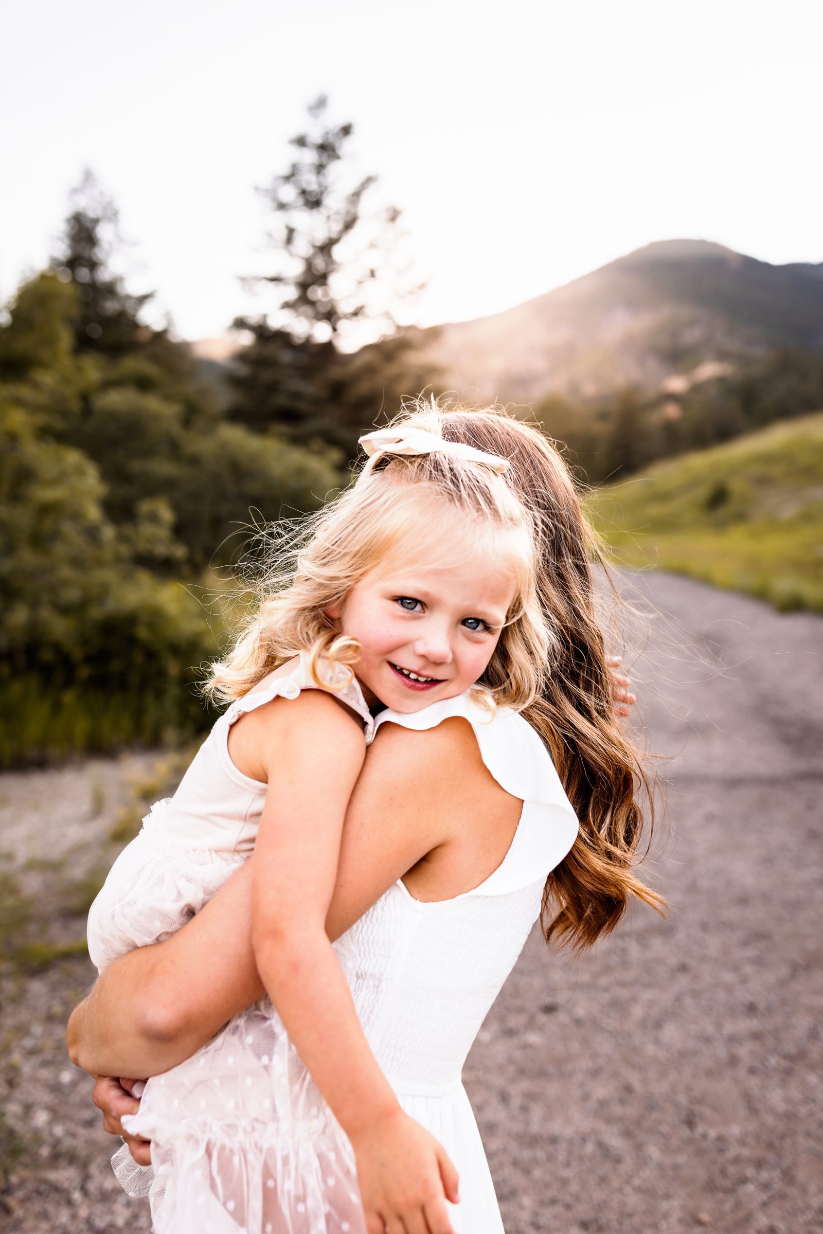 mom holding daughter with a mountain backdrop