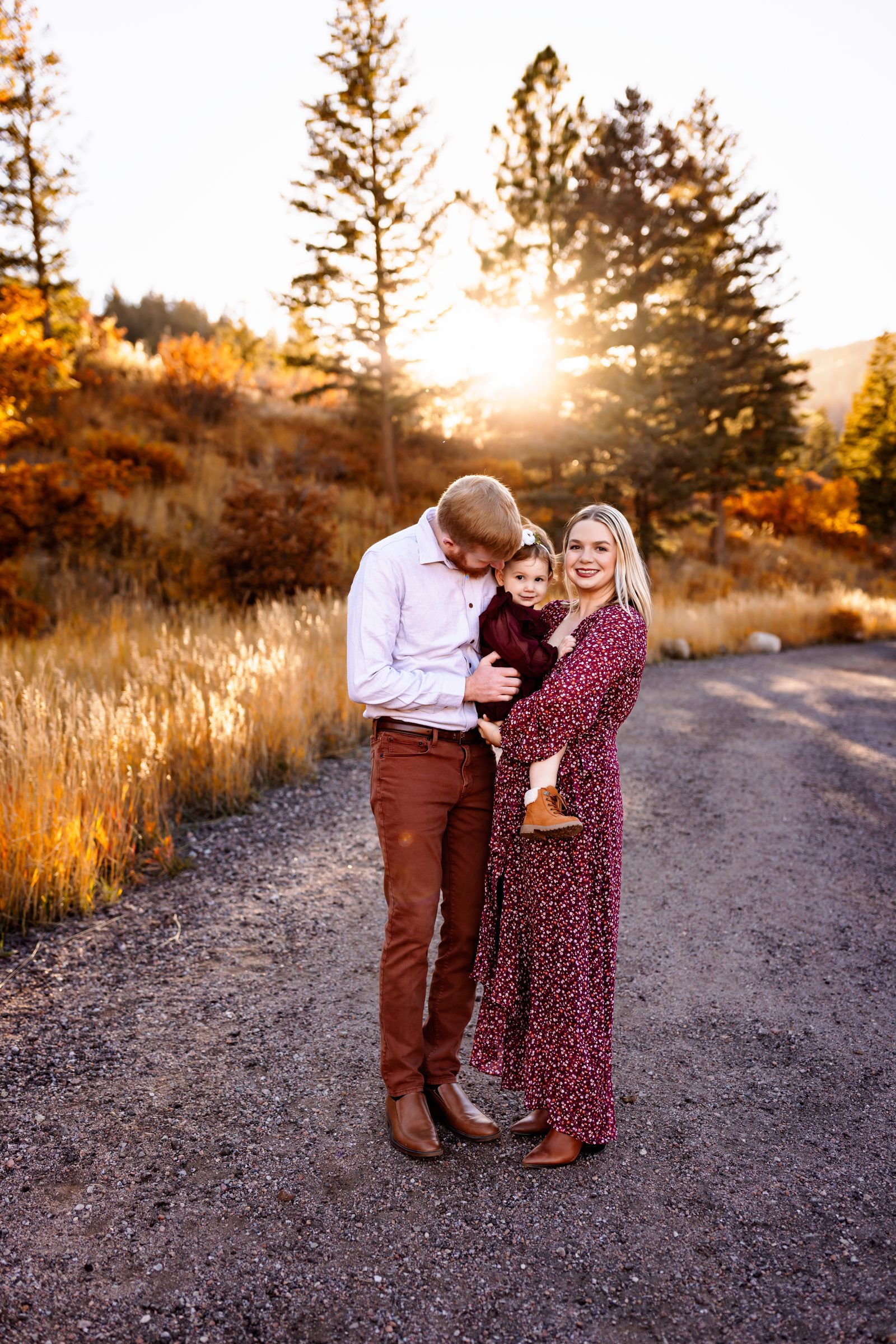Colorado Springs Mini Sessions 2026 featuring a family of three standing together on a mountain road at golden hour