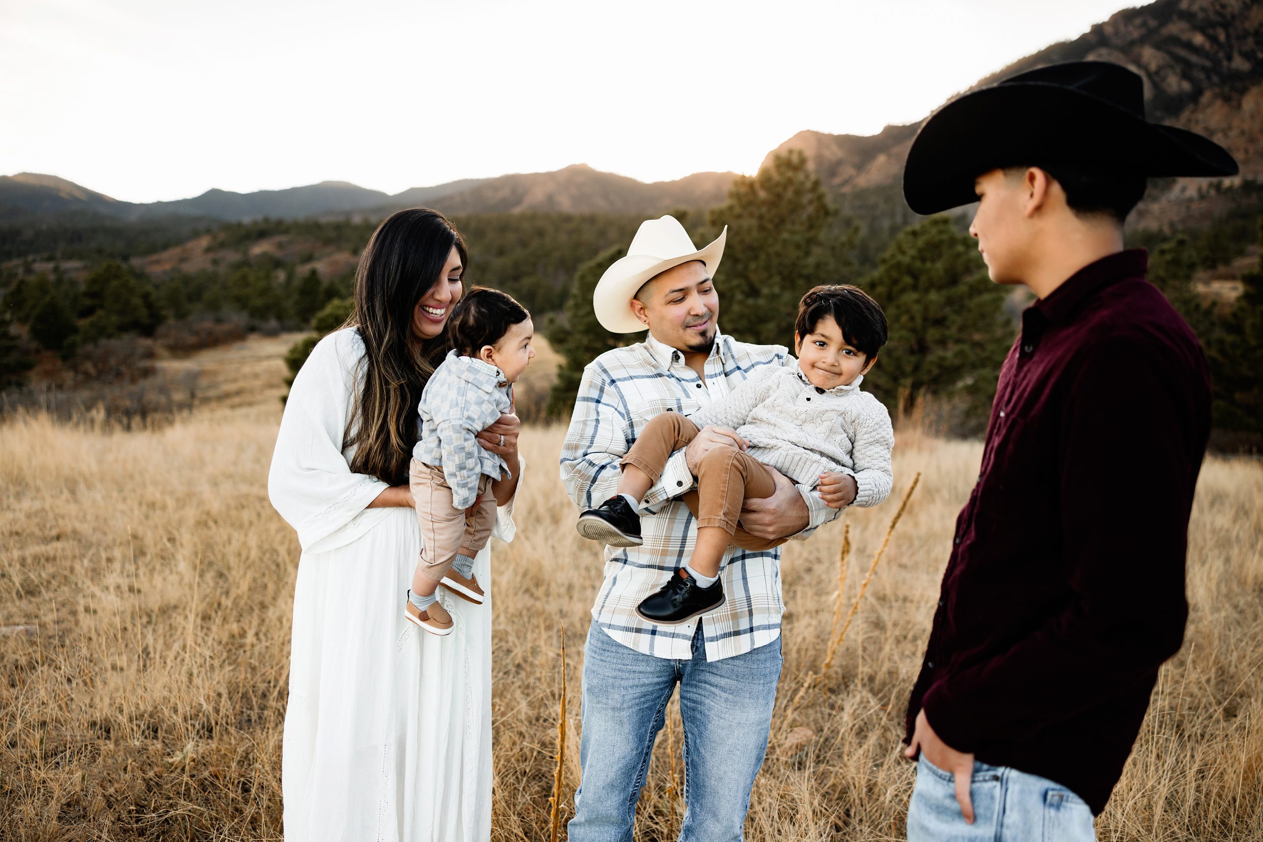 Close-up  capturing parents holding young children with warm smiles and mountain views behind them