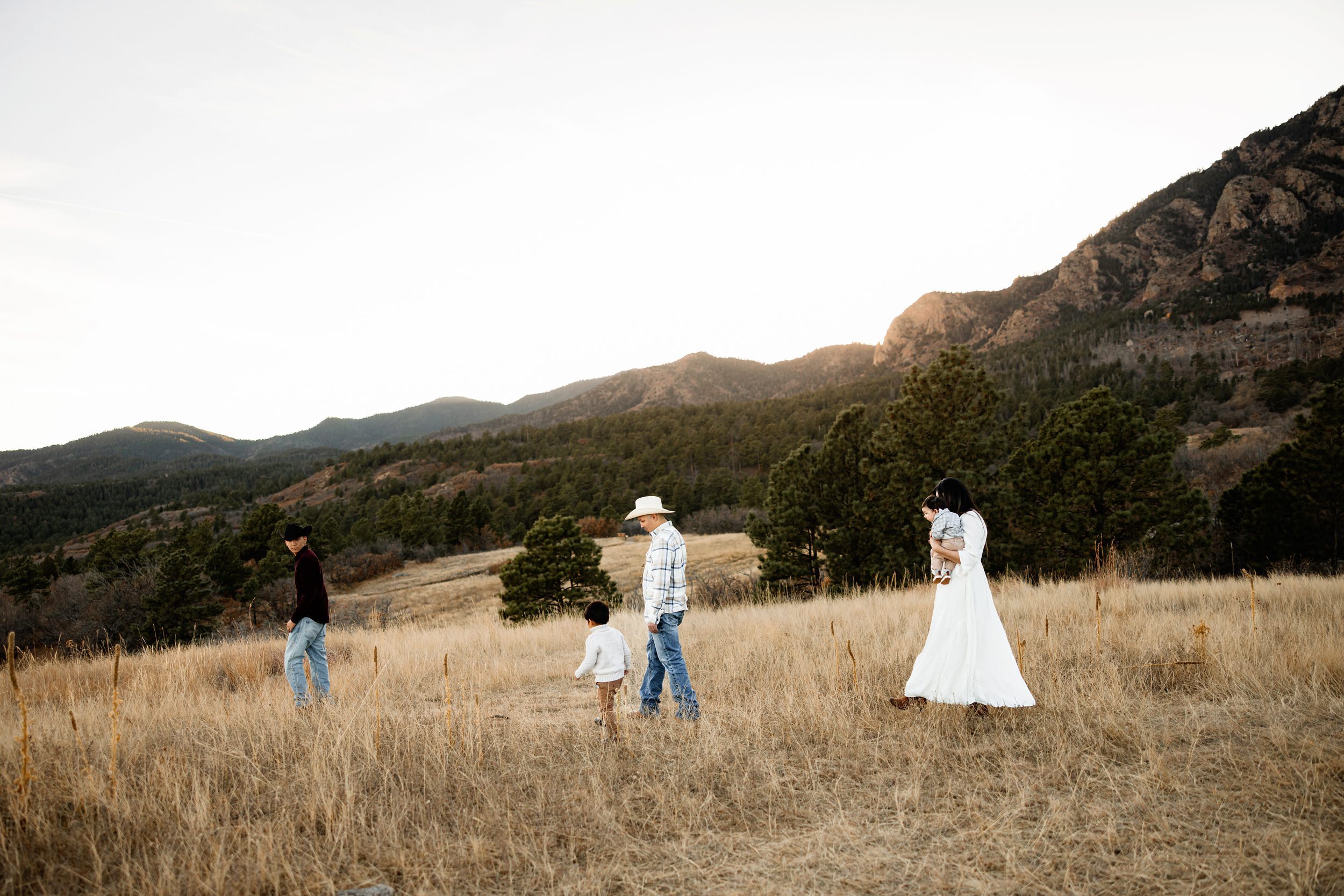 Playful family photos showing parents and kids walking through tall grass during a relaxed outdoor session