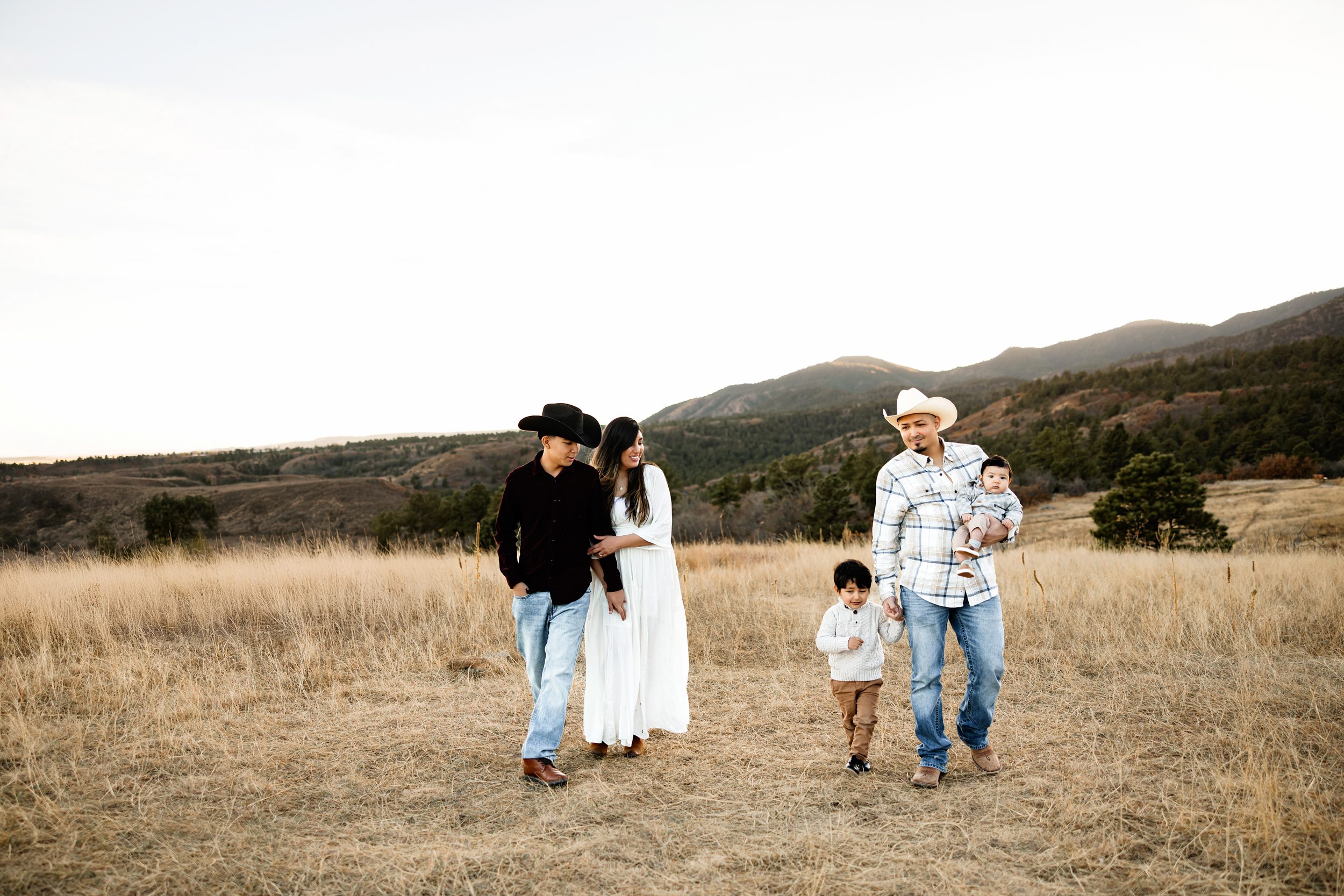 Candid photo of a family walking through an open field with scenic mountain views at golden hour