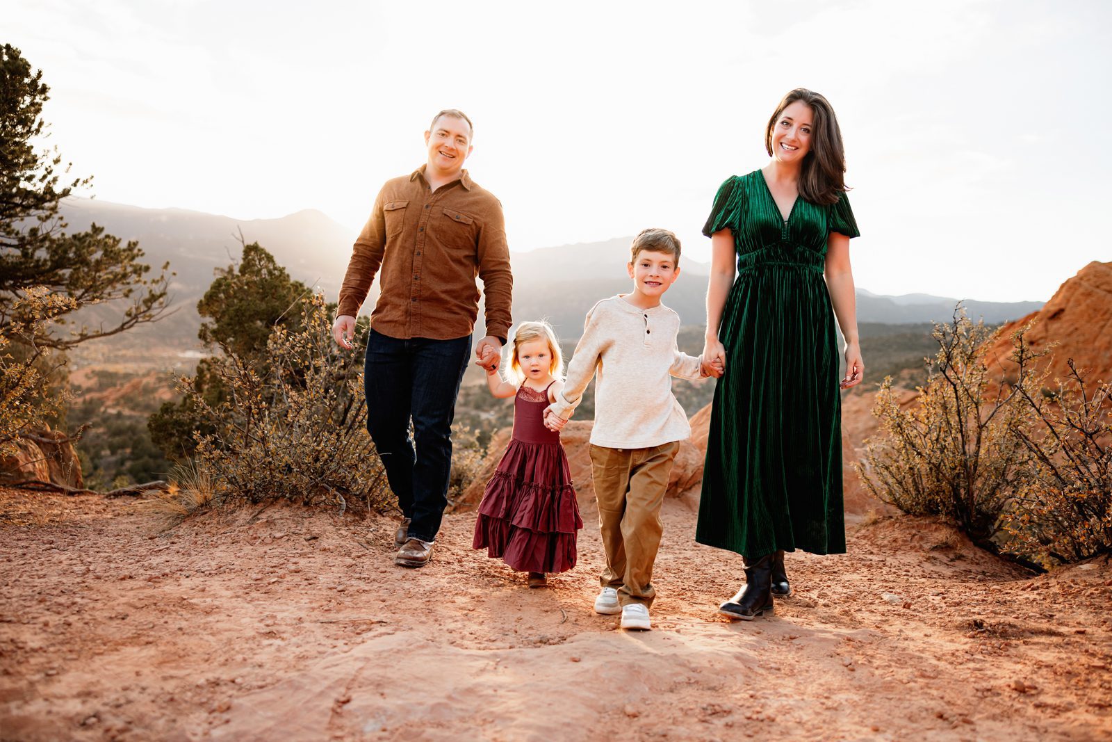 Holiday photos at Garden of the Gods with family walking through iconic red rock landscape, natural candid moments at sunset