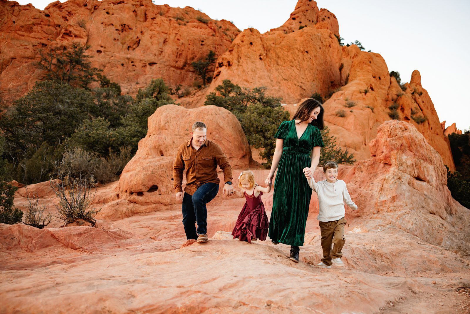 Family walking hand in hand along a rocky trail with mountain views and soft evening light in Colorado Springs