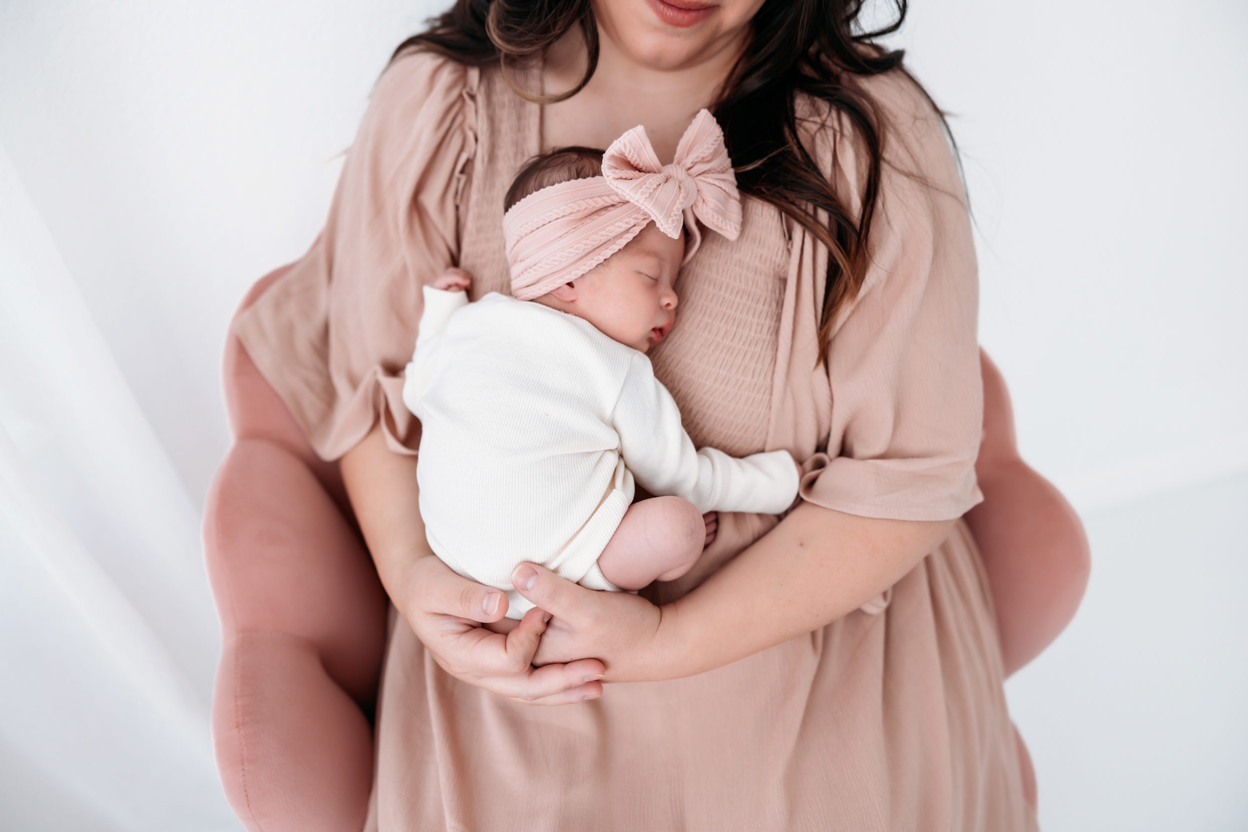 Newborn session in Colorado Springs featuring mom holding a sleeping baby wrapped in soft neutral tones