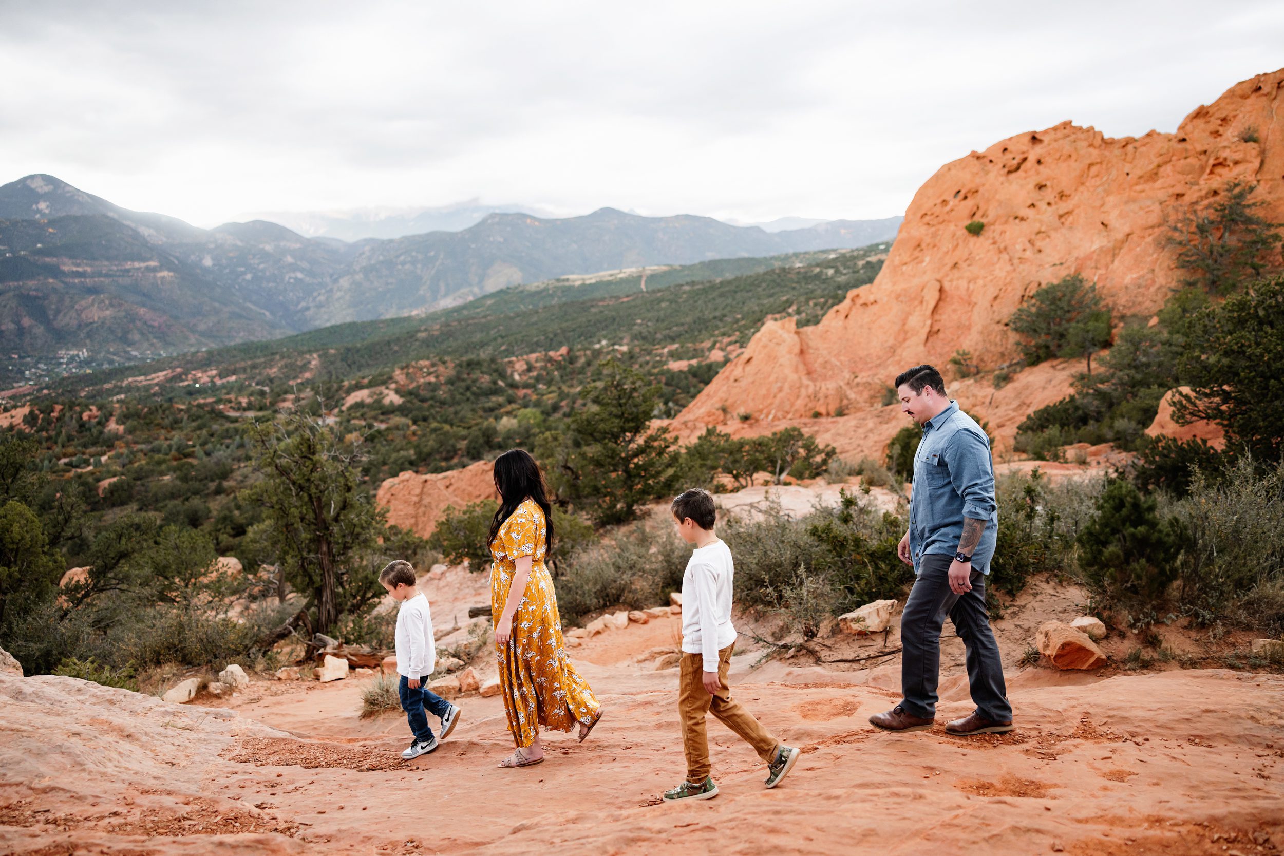 

Family walking together on red rock trails at Garden of the Gods under soft cloudy skies, showing weather changes on your session day